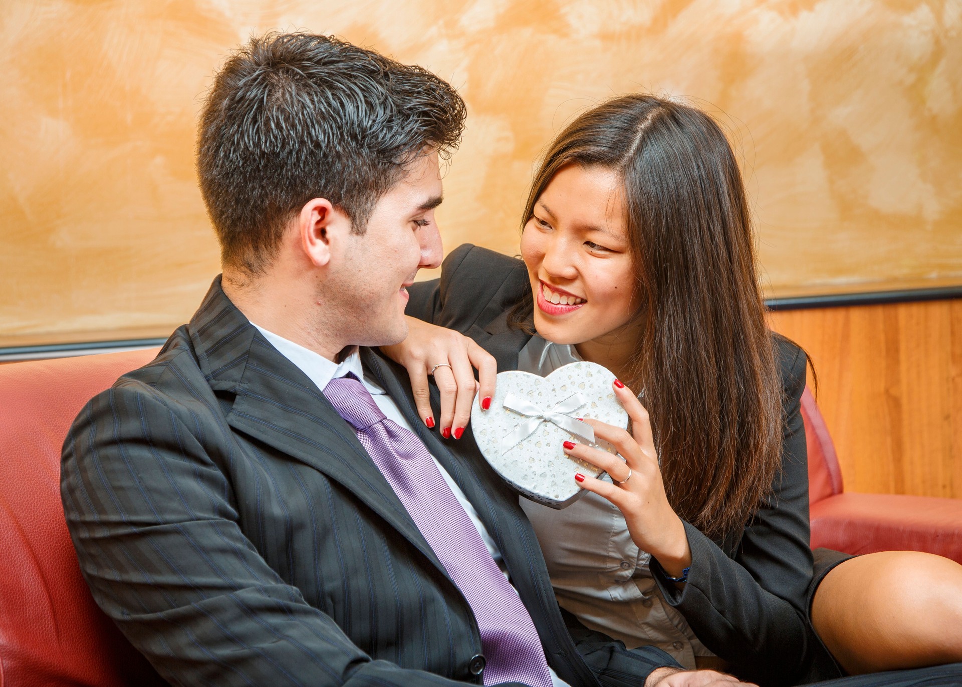 Young couple smiling and holding heart shaped gift